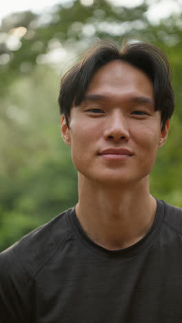 Vertical-Video-Portrait-Of-Smiling-Mid-Adult-Man-Exercising-Doing-Work-Out-Outdoors-In-Forest-Wearing-Sports-Clothing-Shot-In-Real-Time-1